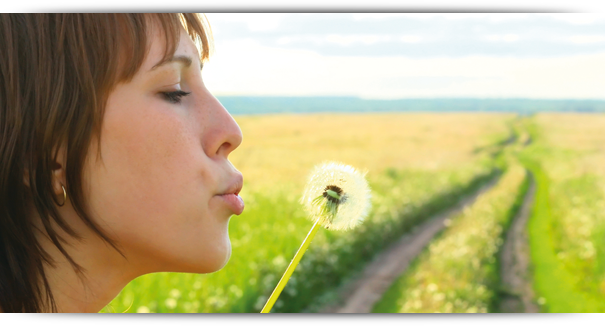 Homöopathie Frau pustet eine Pusteblume