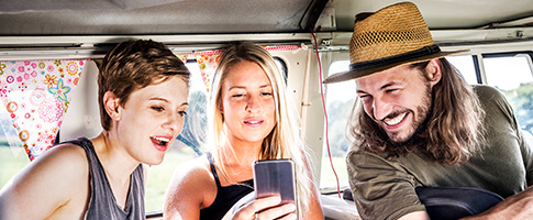 Zwei Frauen und ein Mann schauen auf ein Smartphone